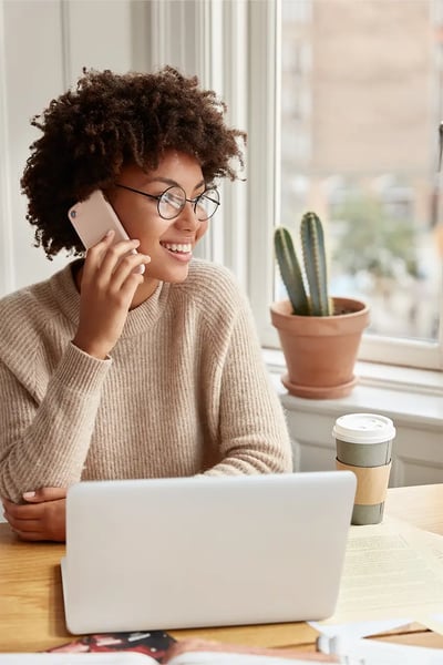 woman looking at copywriting services offered on her computer and talking on the phone